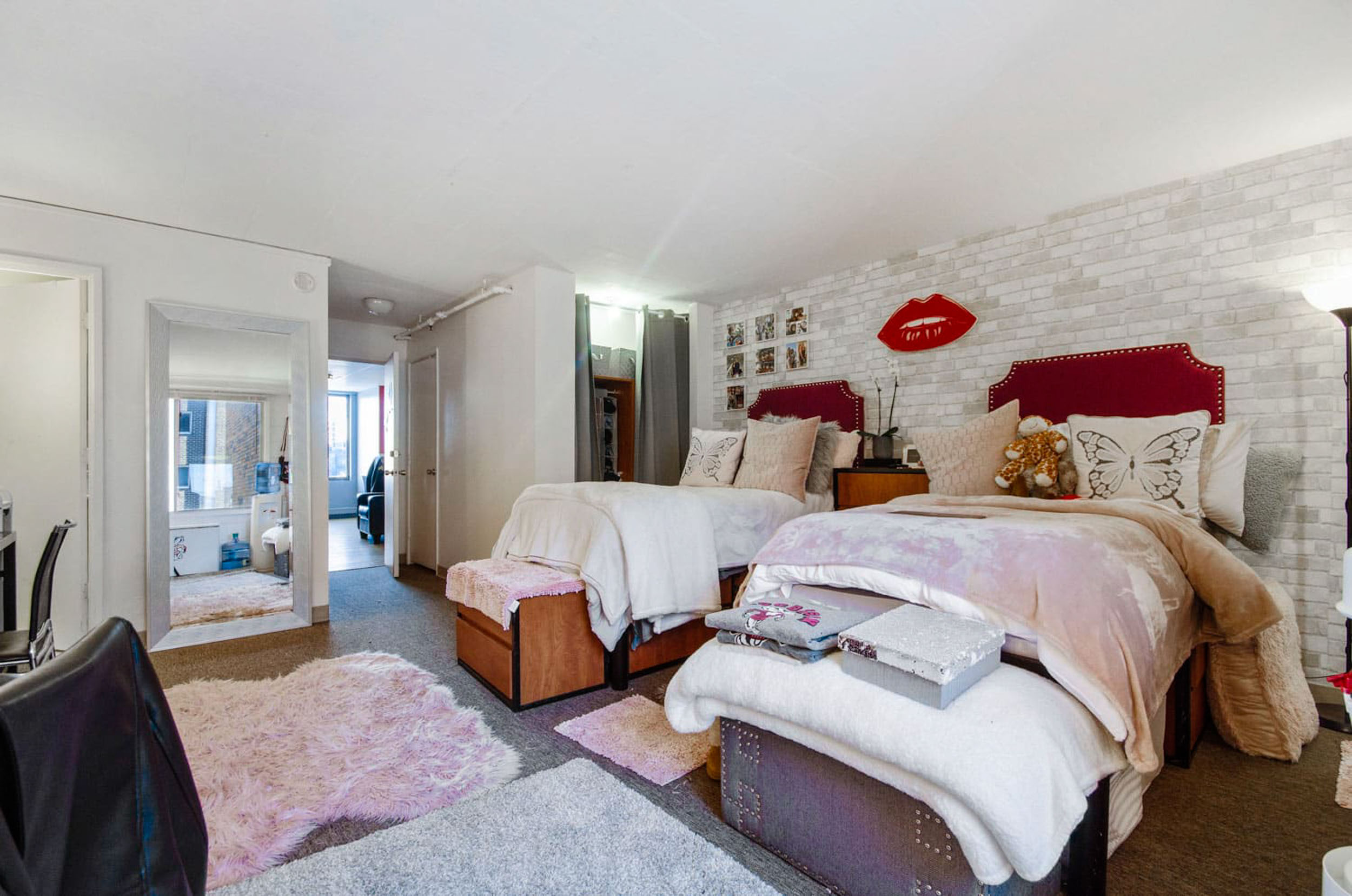 Shared apartment room with two twin beds and pink white and red decor